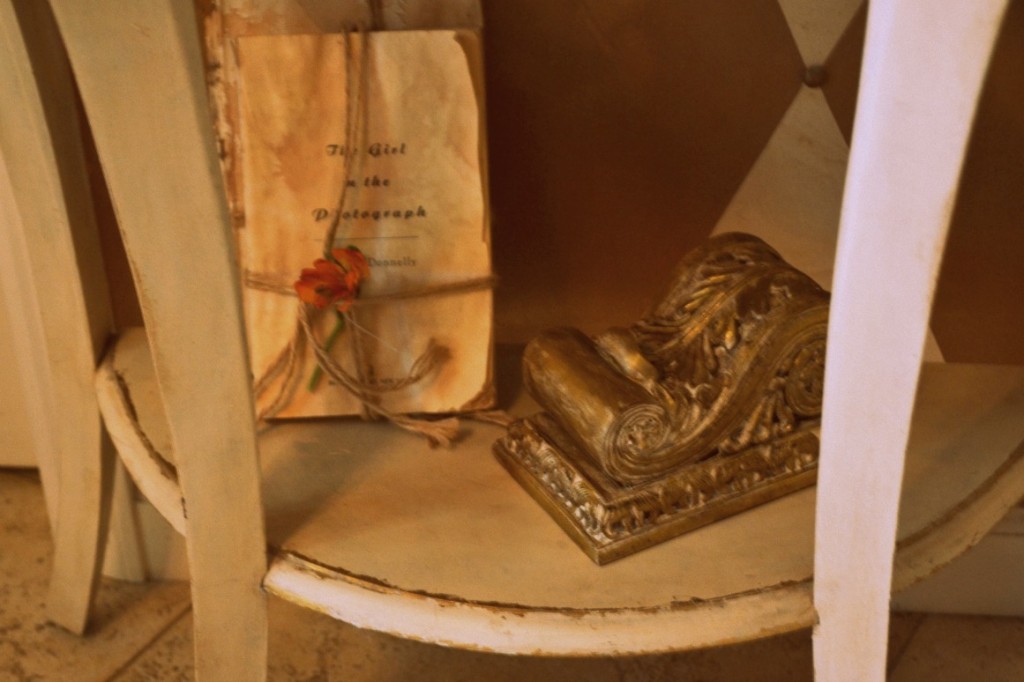 entry table with old, aged books and a sconce as decoration