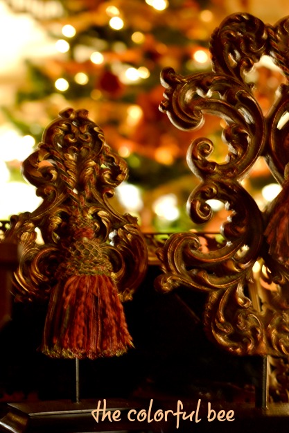 scrolled acanthus ornaments with Christmas tree and lights in background